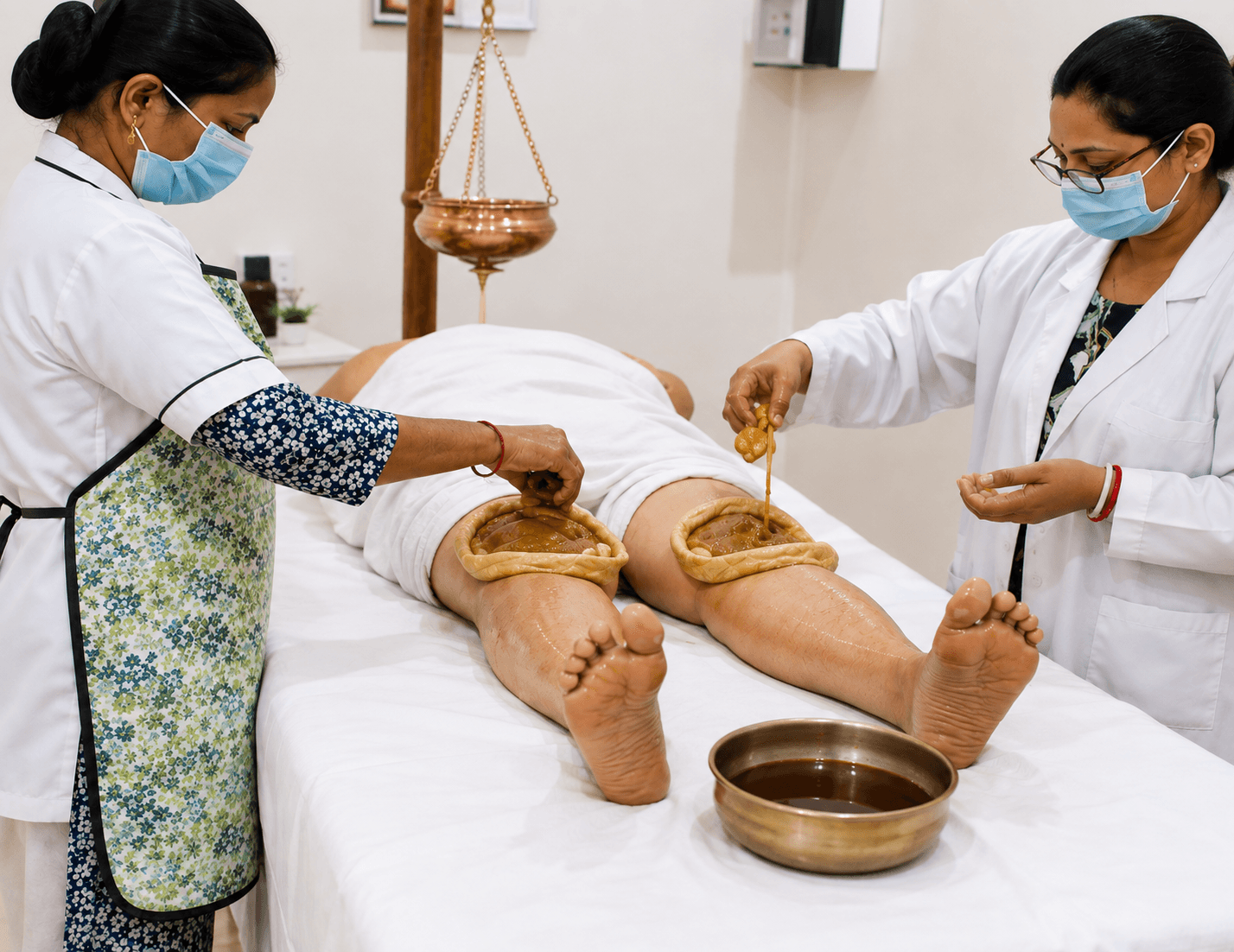 Therapist performing classical Panchakarma Abhyangam with medicated oil in a calm therapy suite.